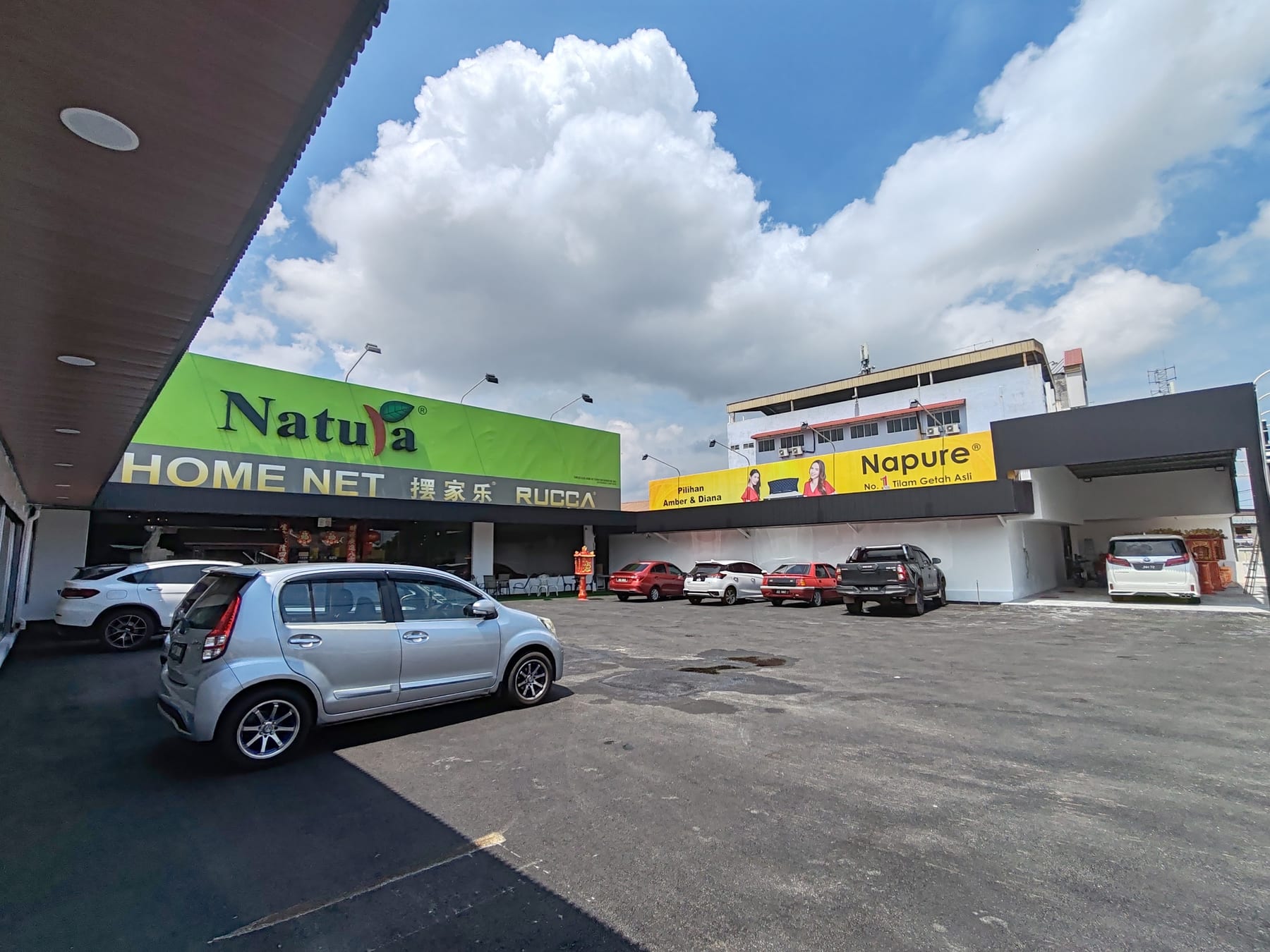 The Home Net showroom on Jalan Salleh in daylight: a long shoplot row with the HOME NET signboard above it and a large private carpark in front.